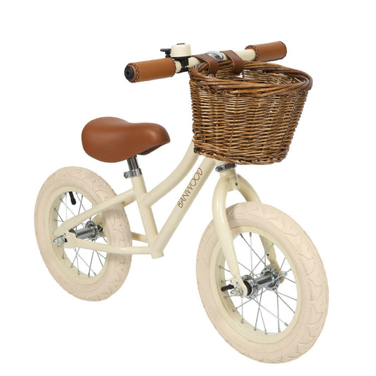 Children's balance bike with a wicker basket on a white background