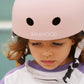 Child wearing a pink helmet with 'Banwood' branding against a blurred background
