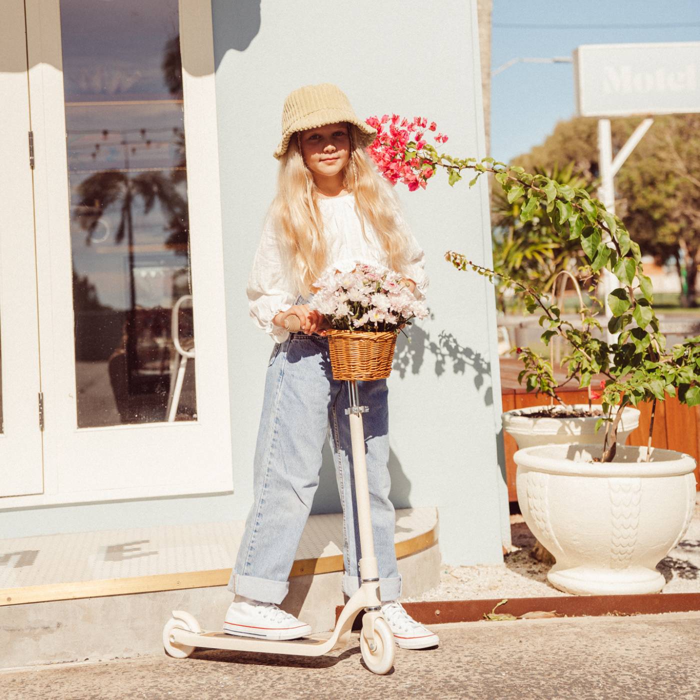 Person with a scooter and flowers standing outdoors near a building.
