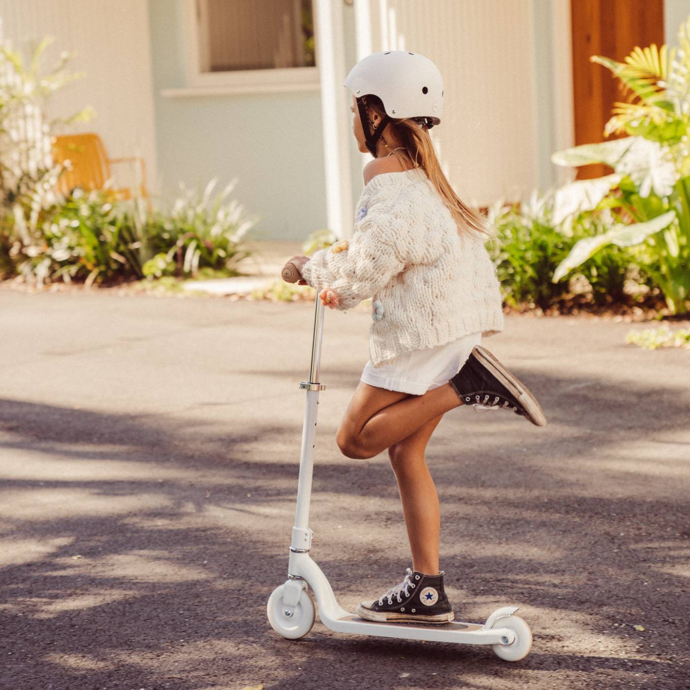 Person riding a scooter on a residential street with a helmet on