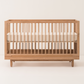 Wooden crib with white mattress on a beige background