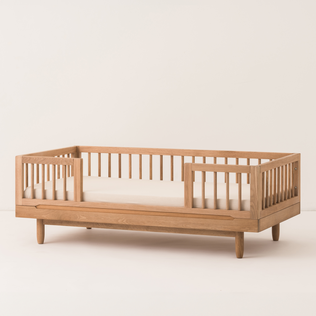 Wooden crib with a white mattress on a light beige background