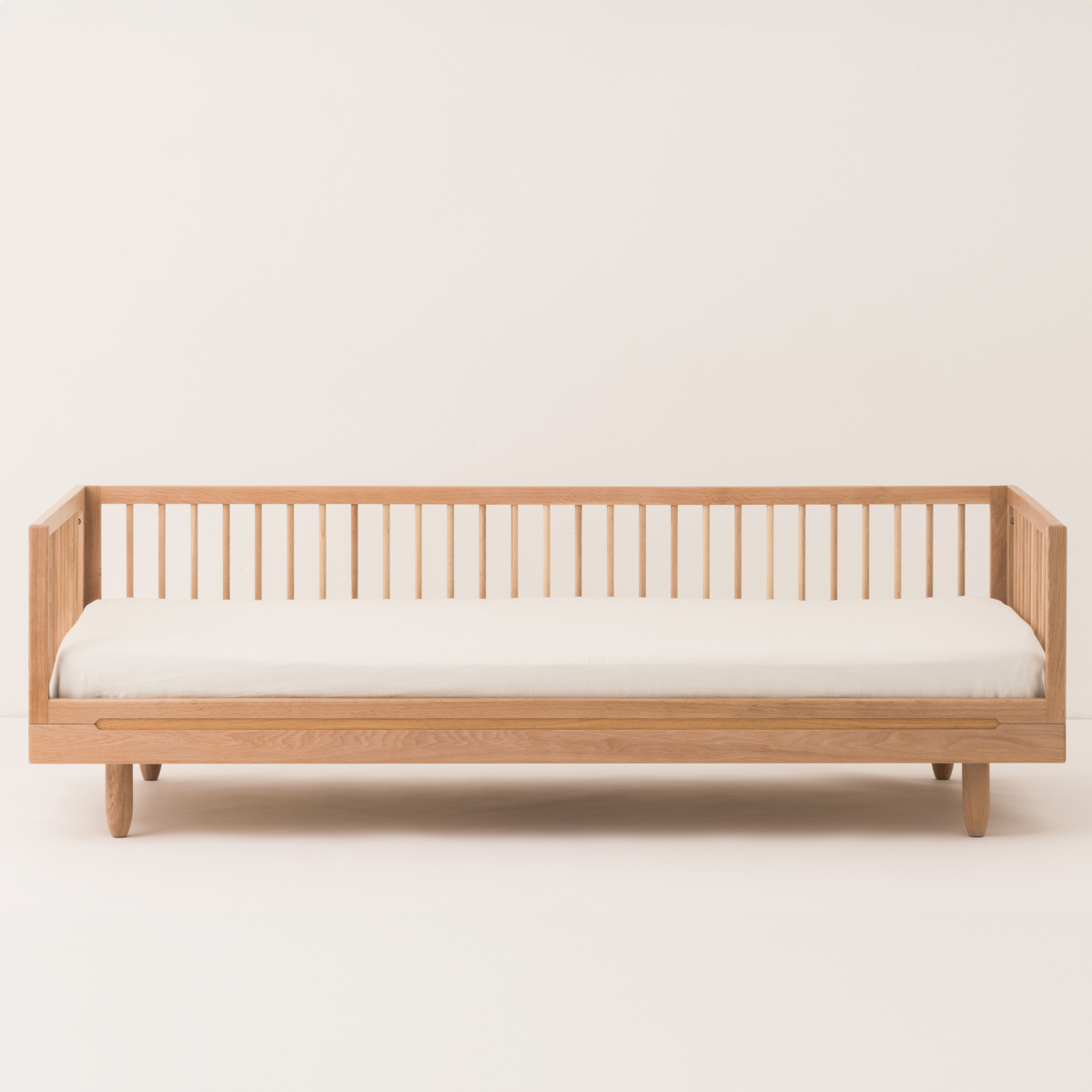 Wooden bed frame with white mattress on a light background