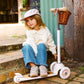 Child sitting on a scooter with a basket in an outdoor setting