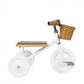White children's tricycle with wooden seat and basket on a white background